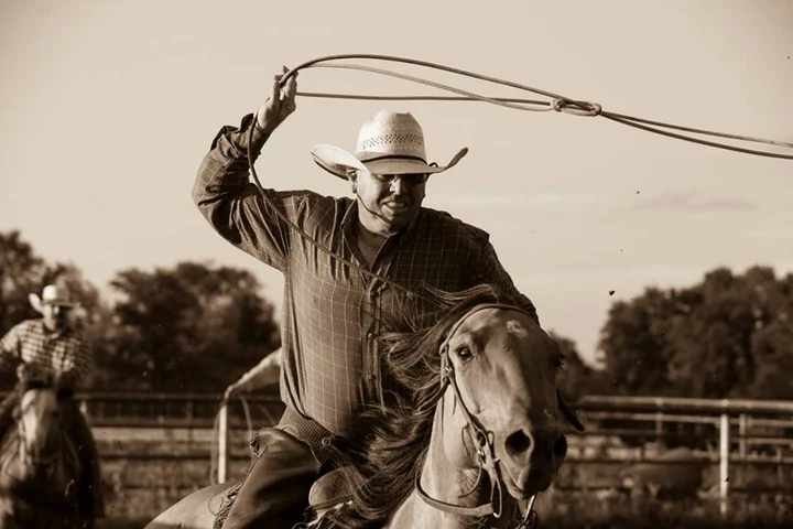 A rider on horseback swinging a rope in a photograph from Three Wooden Crosses Cowboy Church’s gallery.